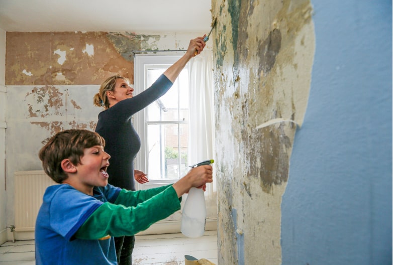 mother and son stripping wallpaper